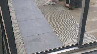 Het lijmen van gebakken tegels op een cementdekvloer voor buiten